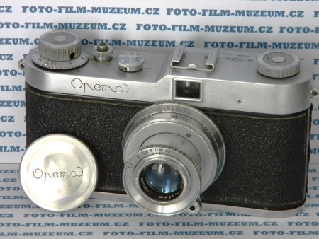 Aparát na 35mm kinofilm. Produkuje zajímavý formát 24 x 32mm. 40 snímků na 1 filmu. Objektivový závit 38mm. Výroba od r.1955??? Objektiv na výsuvném tubusu. Transport spřažený s natahováním závěrky. Plátěná horizontální závěrka 1/25s. - 1/500s. + B.
