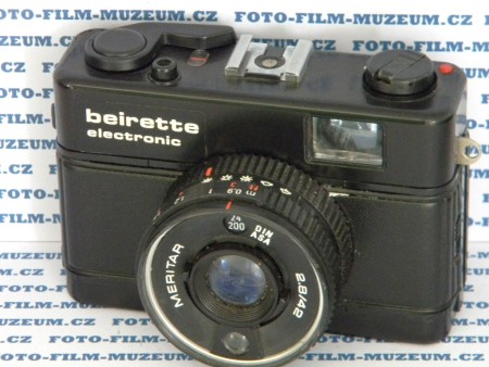 Výroba od r. 1981 do r. 1988. Měření Cds TTL. Elektronicky řízená centrální závěrka s časy 4s. - 1/500s. + B. X-sync. 1/30s. Objektiv Meritar 2.8/42mm.